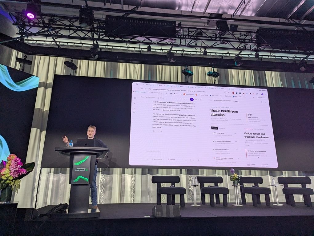 Josh Cooper at the lectern running a live demo of the agent marketplace